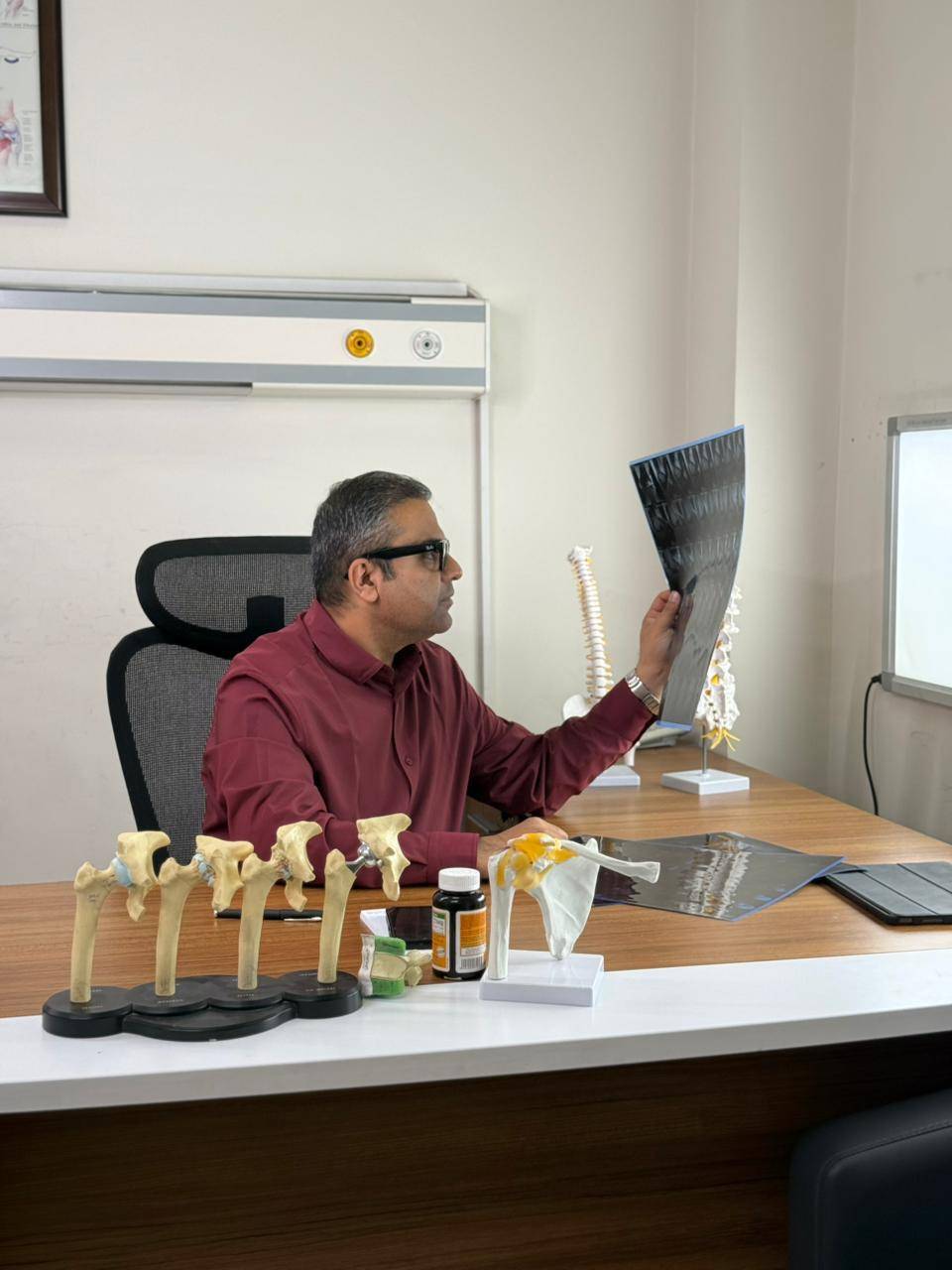 Dr. Ankur Singh examining patient X-ray and joint scans during clinical consultation